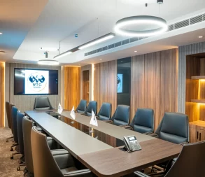 Modern conference room with leather chairs and digital display.