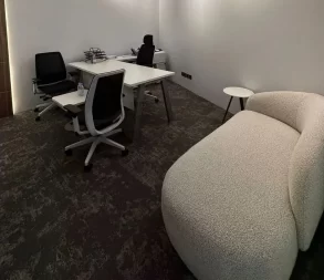 Contemporary office with meeting desk, chairs, and relaxing lounge.